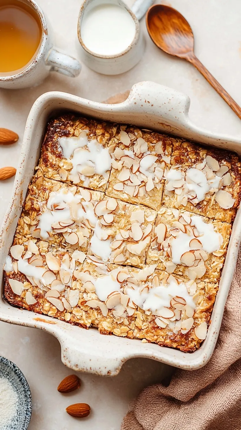 Golden brown almond croissant baked oatmeal topped with sliced almonds in a square baking dish.