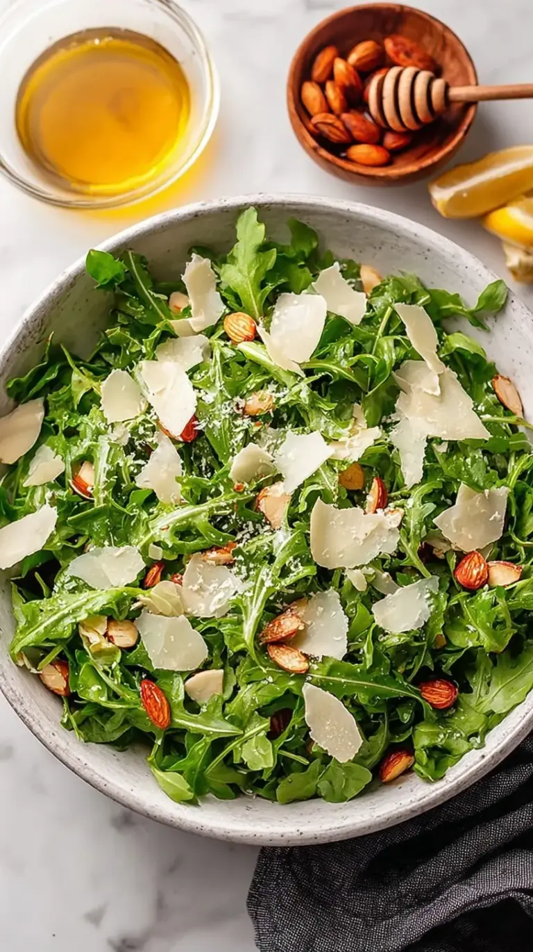 Fresh baby arugula salad with shaved parmesan cheese and lemon vinaigrette on a white plate