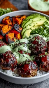 A vibrant grain bowl with glazed barbecue meatballs, roasted broccoli, corn, and a drizzle of green avocado sauce.