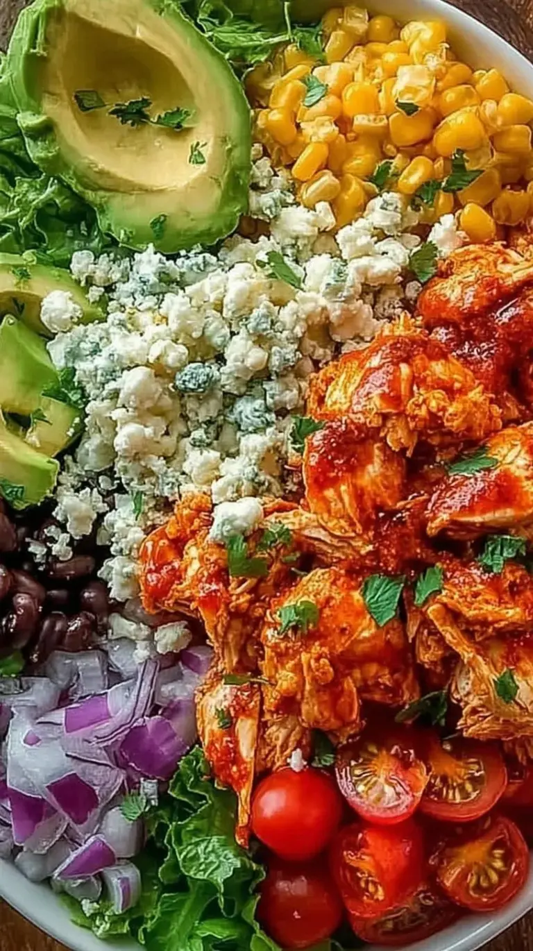 A vibrant buffalo chicken bowl with shredded chicken, white rice, carrots, and celery drizzled with ranch dressing.