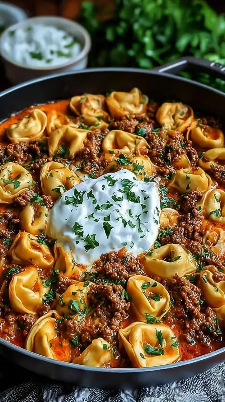 A skillet of cheesy beef enchilada tortellini garnished with fresh cilantro