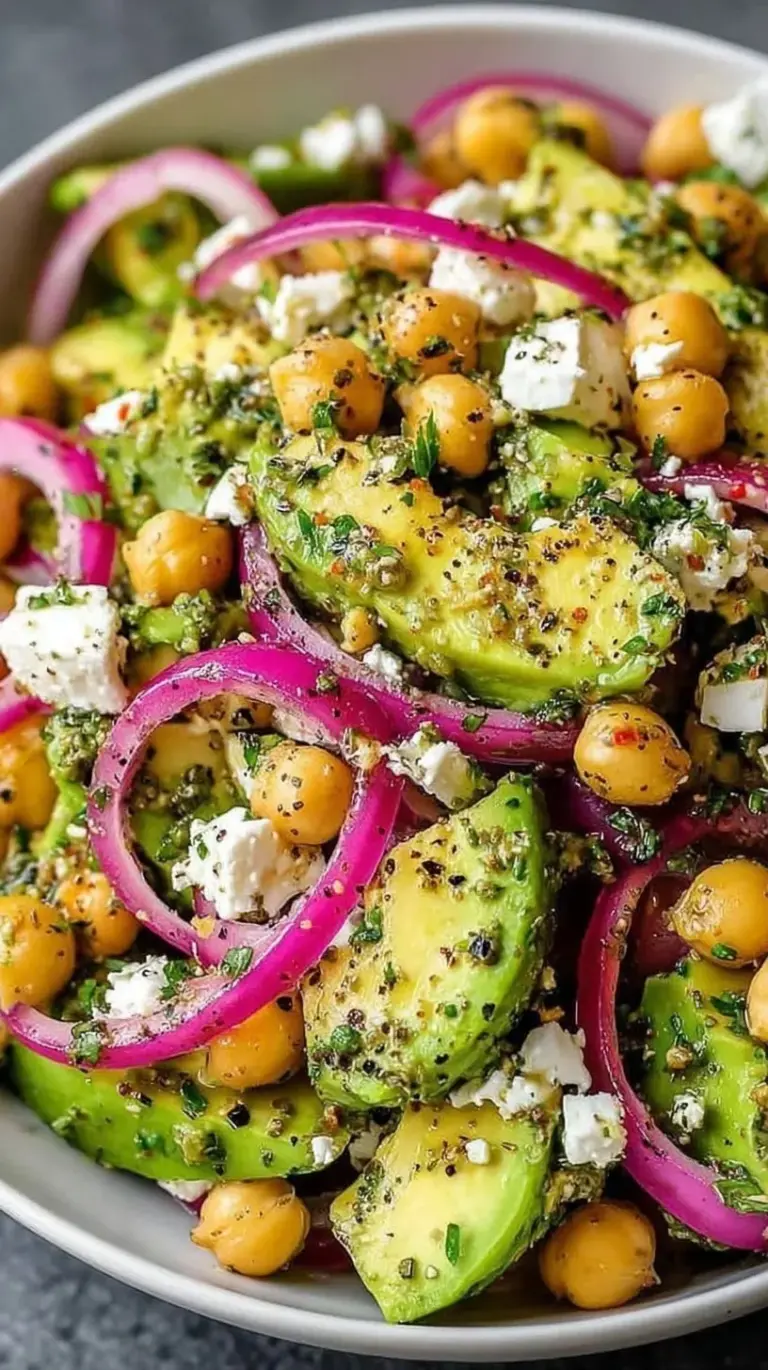 A bright Mediterranean salad with chickpeas, diced avocado, crumbled feta, and cherry tomatoes in a white bowl.