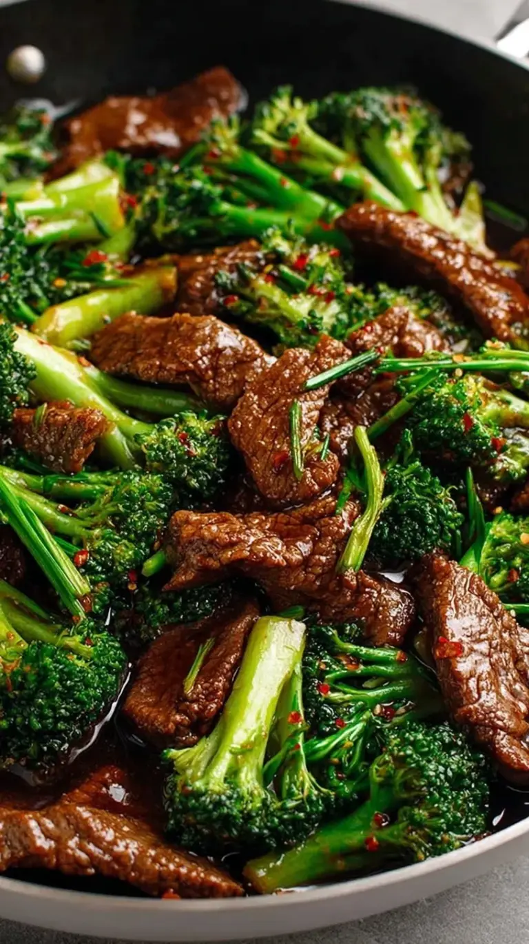 Tender sliced beef and bright green broccoli florets coated in a glossy brown sauce in a black wok.