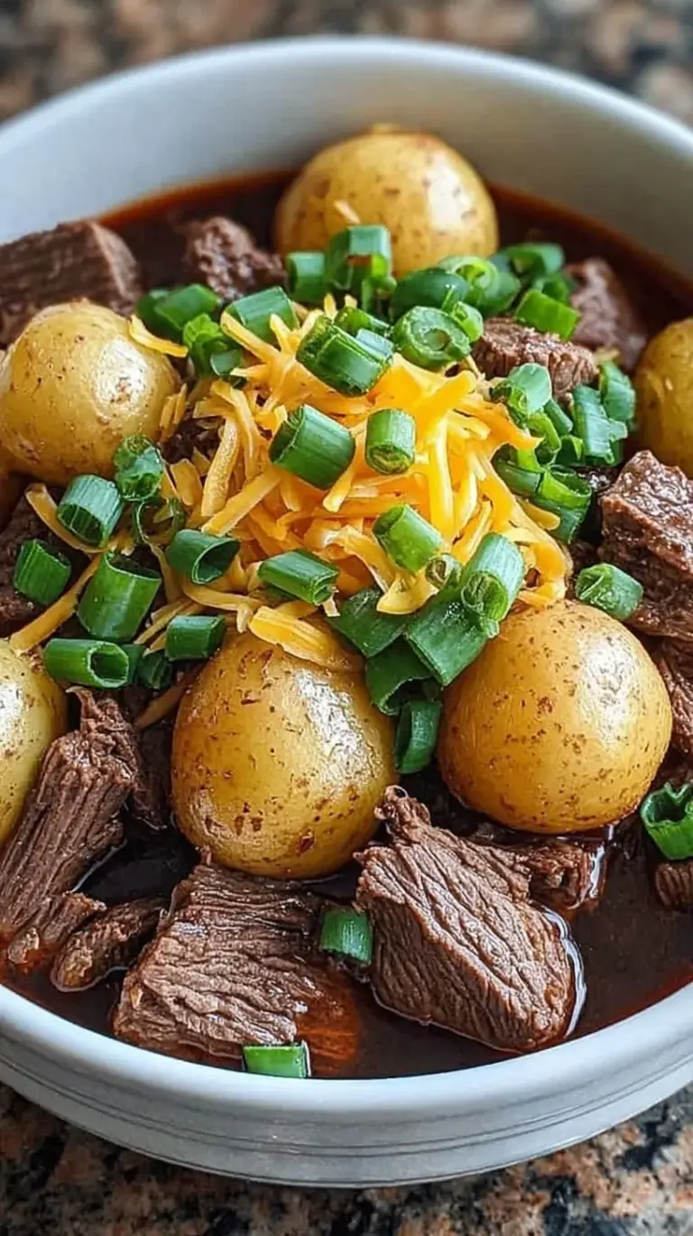 Slow cooker filled with tender steak cubes, potatoes, melted cheddar cheese, and crispy bacon bits.