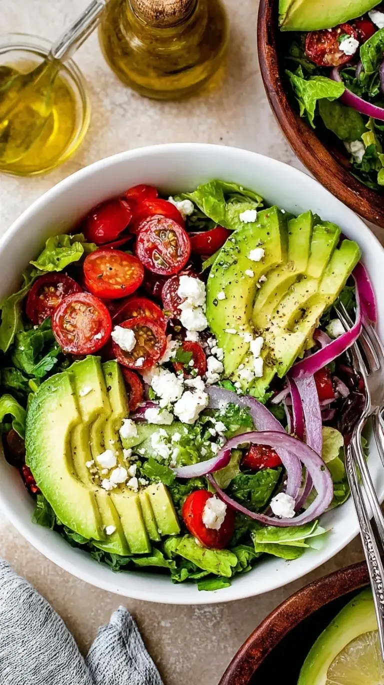A vibrant deconstructed guacamole salad with cubed avocado, cherry tomatoes, and red onion in a white bowl.