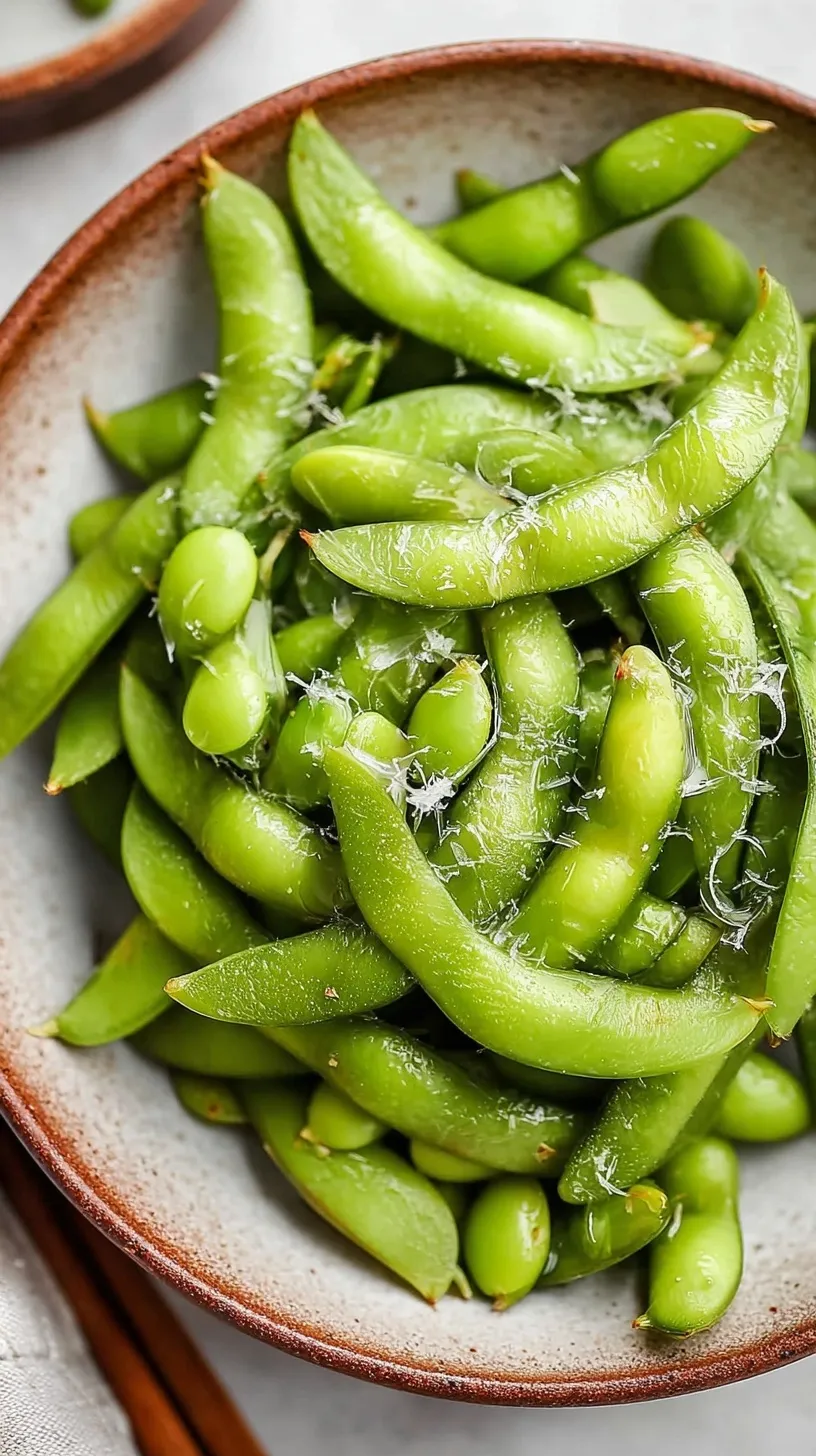 A bowl of bright green steamed edamame pods sprinkled with flaky sea salt