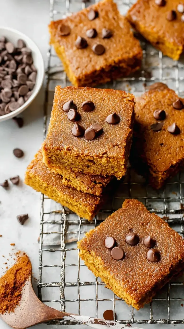 A stack of sliced healthy pumpkin bars on a cooling rack with warm spices