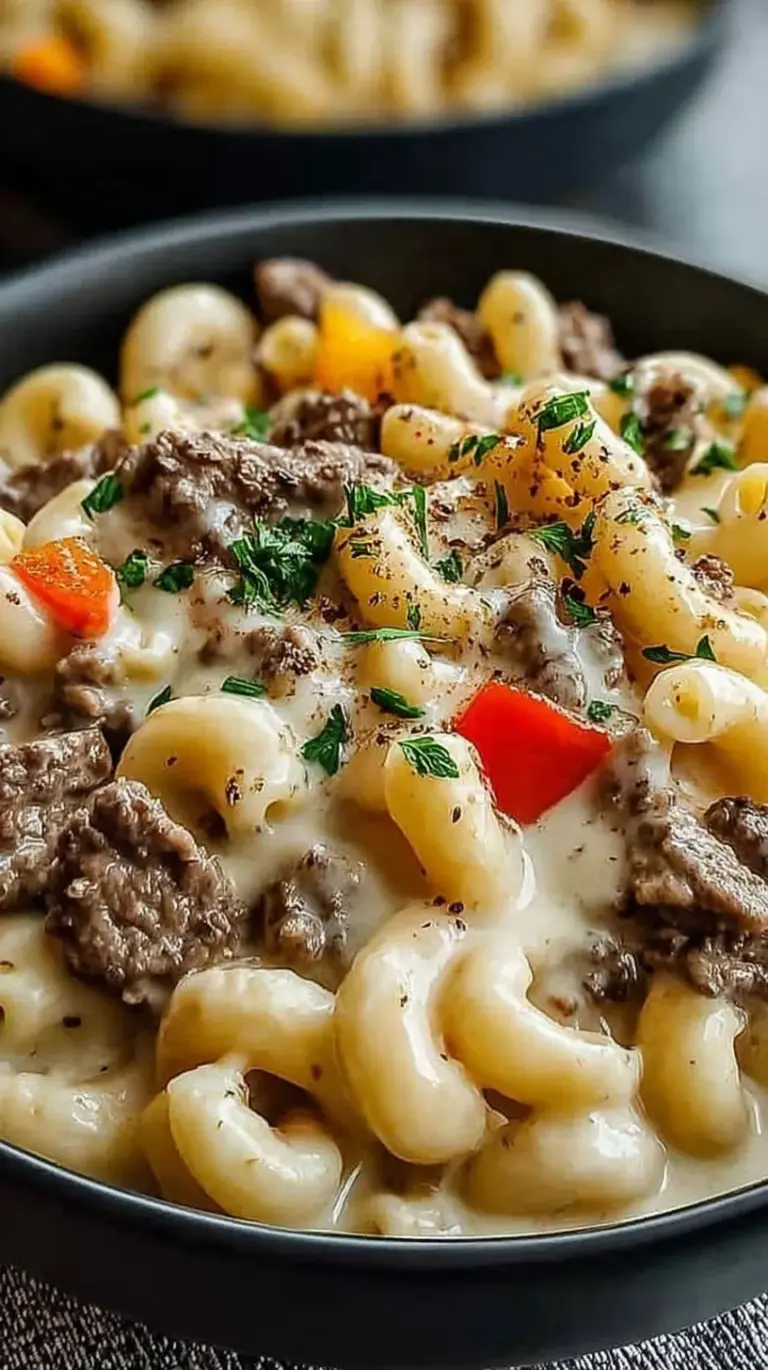 A bowl of creamy high-protein pasta with thinly sliced beef and green bell peppers.