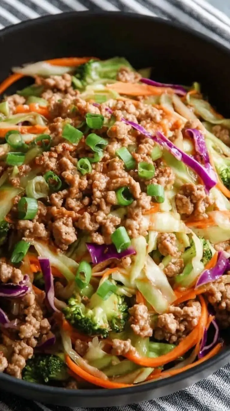 A colorful bowl of ground turkey and shredded cabbage garnished with green onions and sriracha