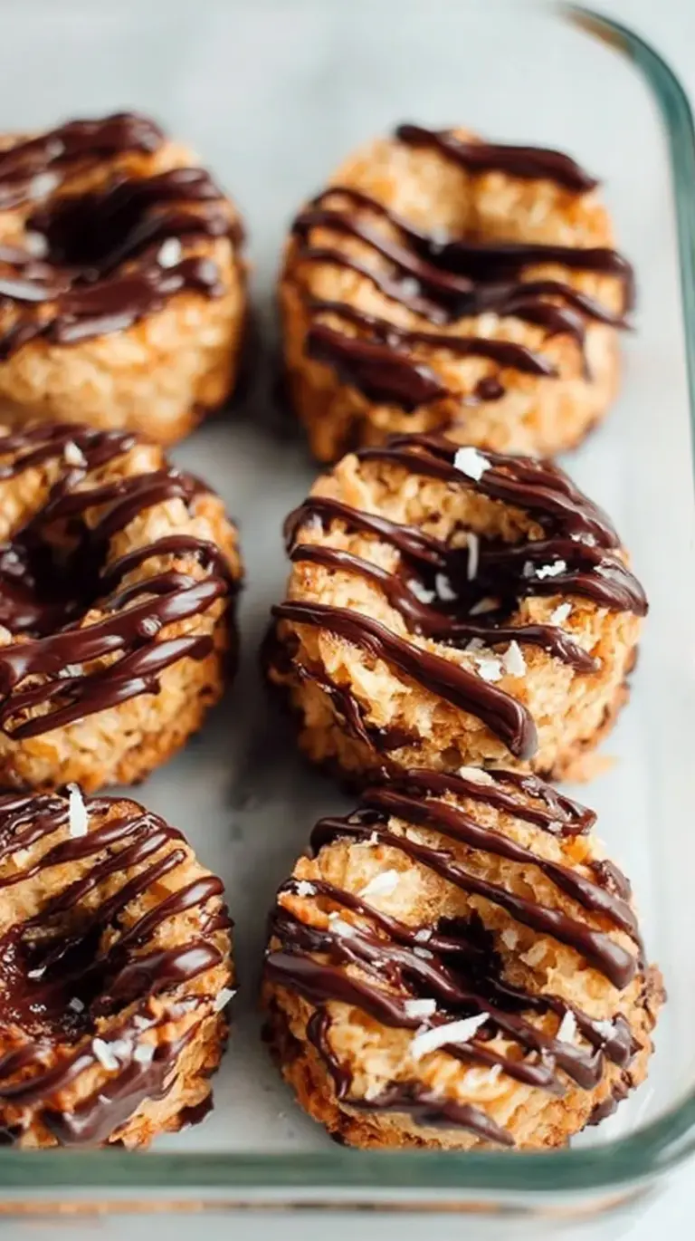 A stack of homemade samoas cookies with toasted coconut, caramel, and chocolate drizzle on a white plate.