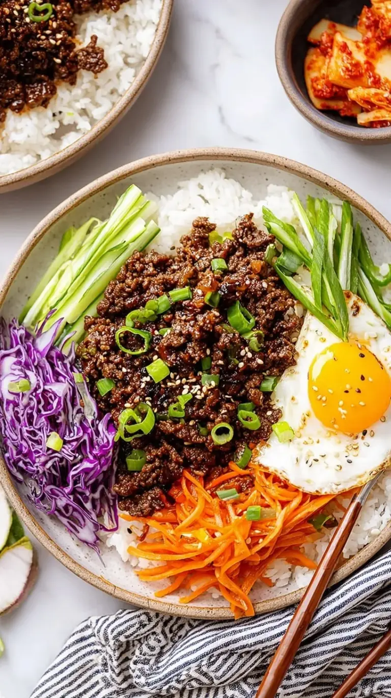 A white bowl filled with white rice and savory ground beef garnished with green onions and sesame seeds.