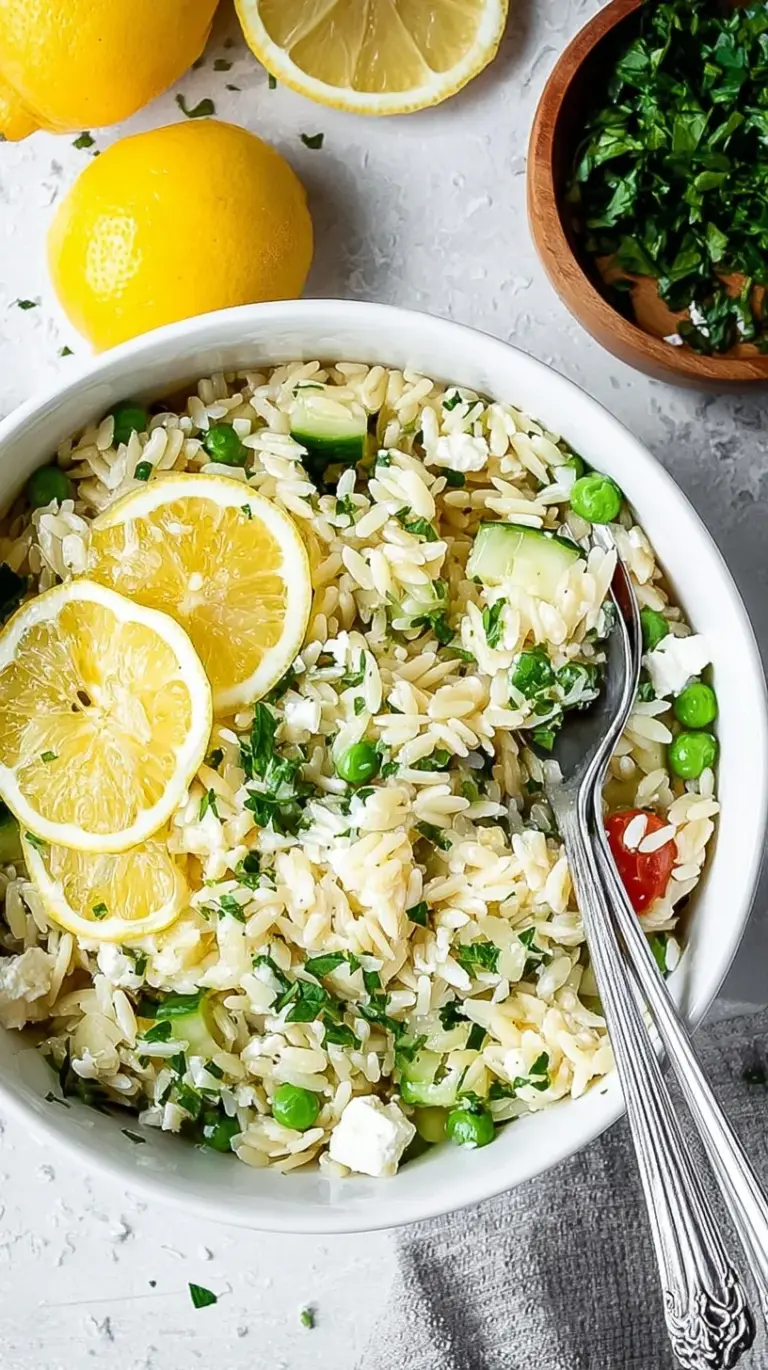 A bright bowl of lemon orzo salad with cherry tomatoes, cucumber, and feta cheese