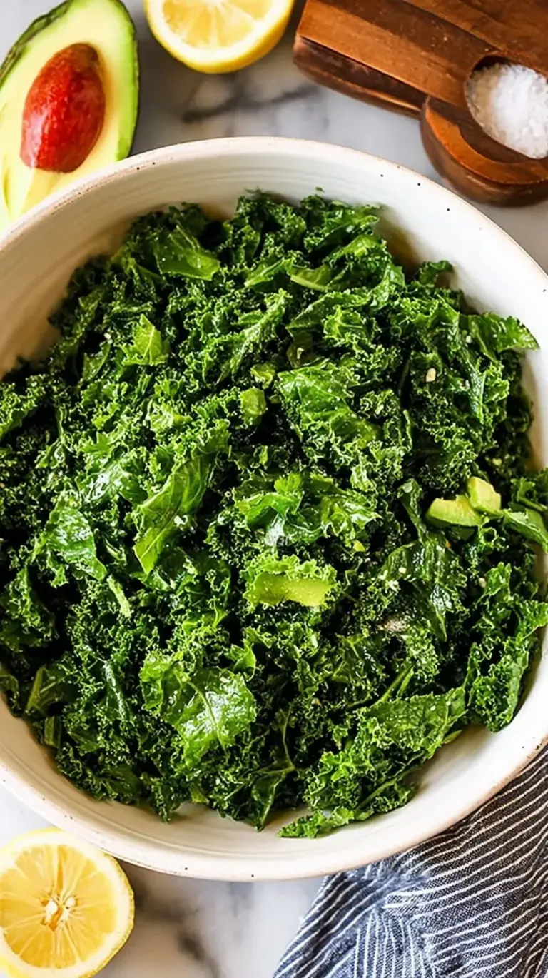 A large bowl of vibrant green massaged kale salad with creamy avocado, sunflower seeds, and dried cranberries.