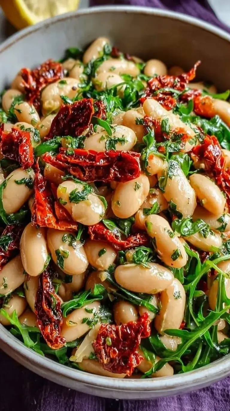 A white bowl filled with creamy cannellini beans, bright sun-dried tomatoes, and fresh green parsley.