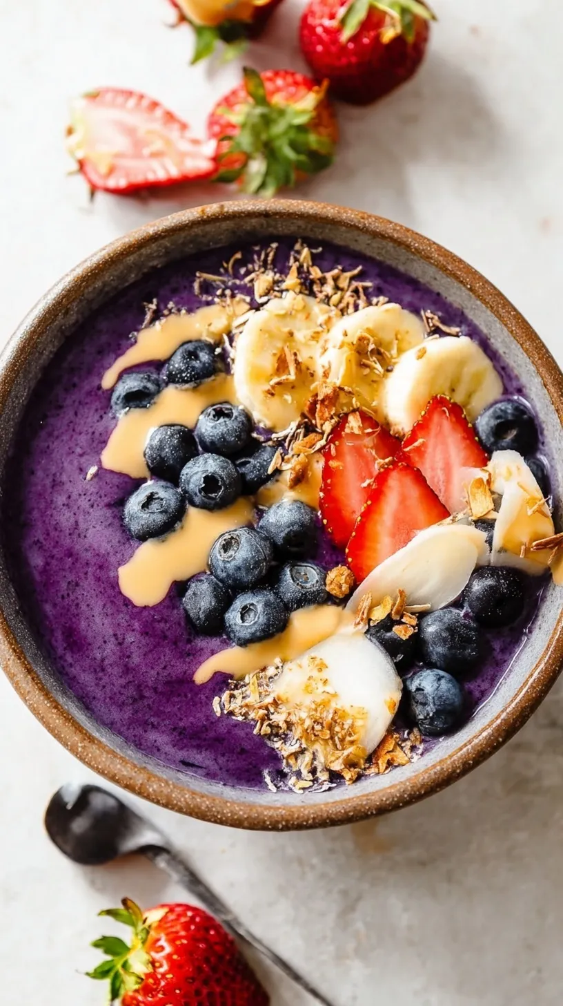 A vibrant purple thick acai smoothie bowl topped with fresh strawberries, banana slices, and granola.