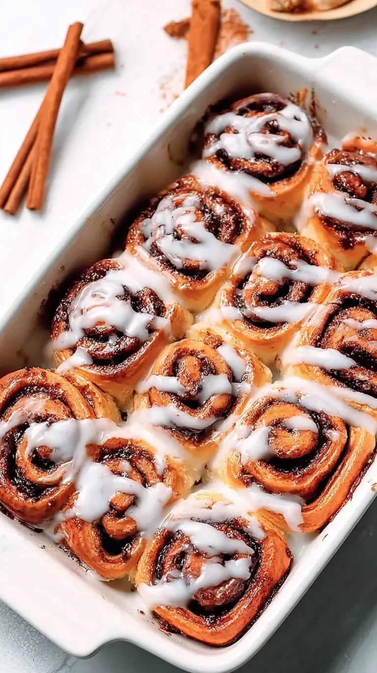 A tray of warm vegan cinnamon rolls with white sugar glaze dripping down the sides.